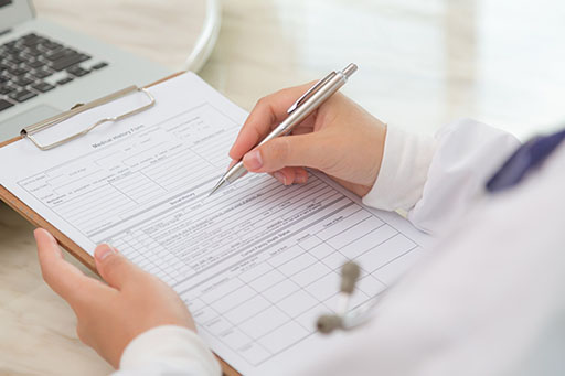 Person filling out dental patient information form on clipboard