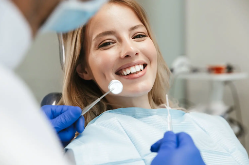 Smiling patient during dental checkup with mirror and dental tools